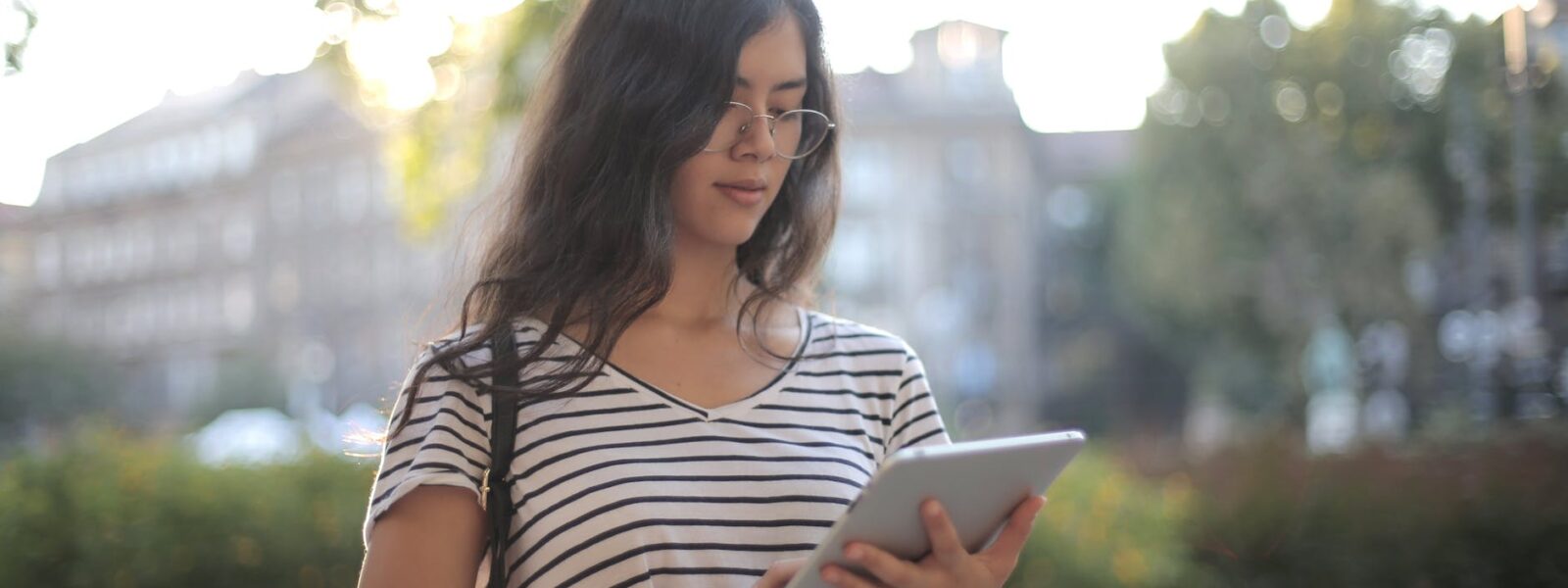 calm pensive female freelancer using digital tablet on street