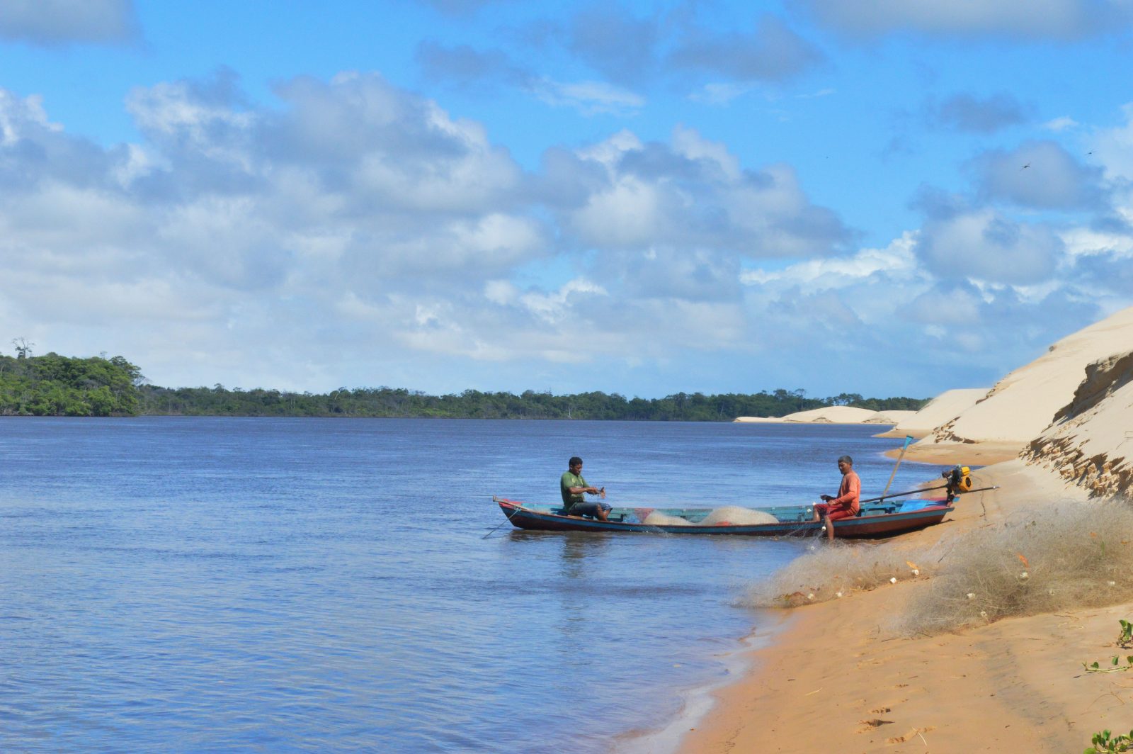 Pescadores em canoa no Rio Preguiças ao lado das dunas de Caburé, no caminho para Atins