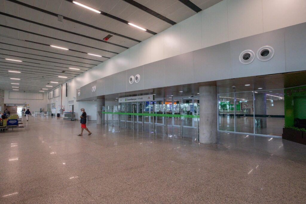 Saguão de desembarque do Aeroporto Internacional de Natal, amplo e iluminado, com as portas de saída ao fundo