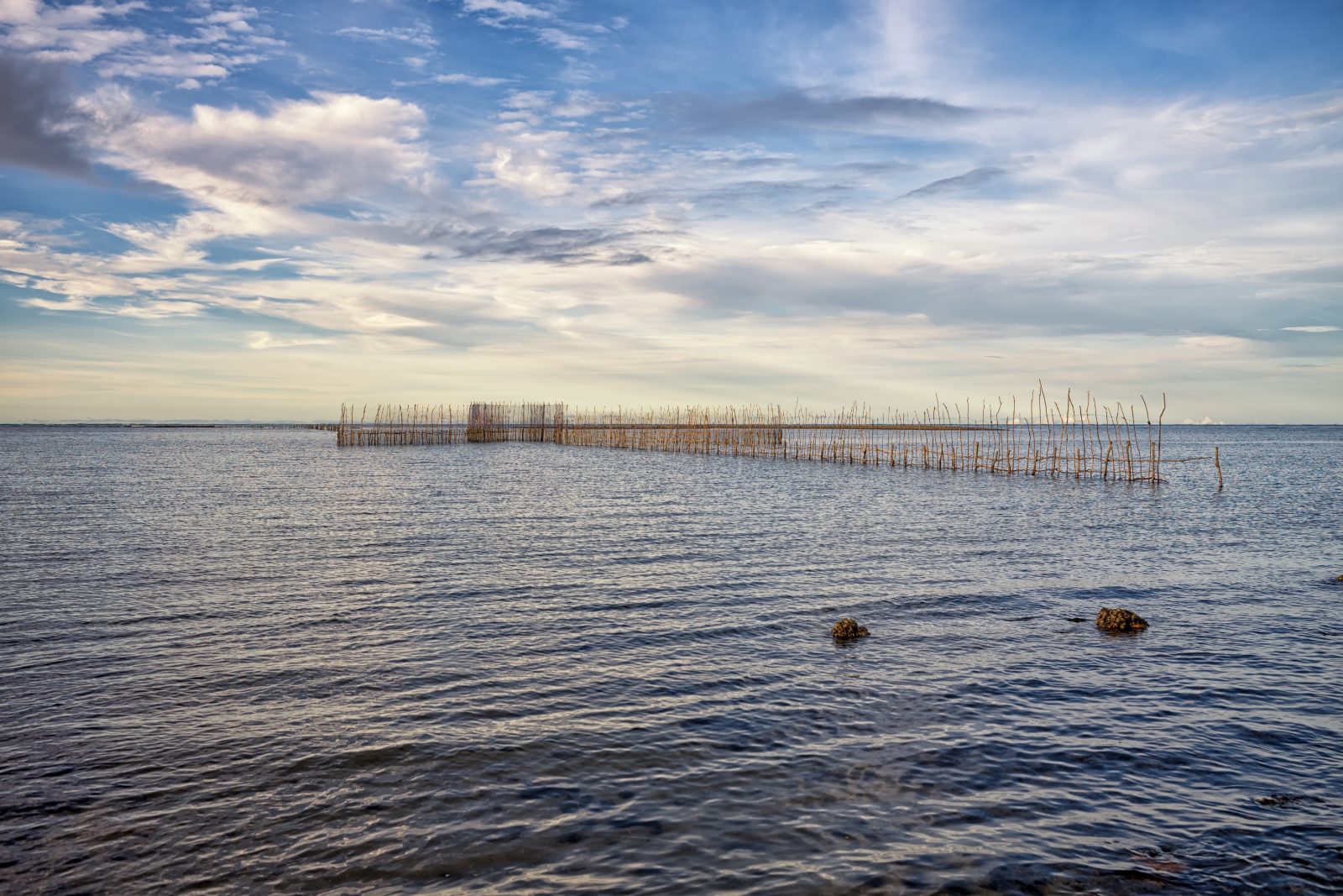 Currais de pesca no mar calmo de Barra Grande sob céu com nuvens