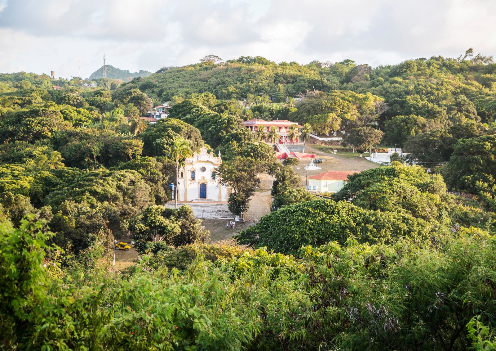 Vista do alto da Vila dos Remédios, em Fernando de Noronha, com a igreja branca cercada de árvores