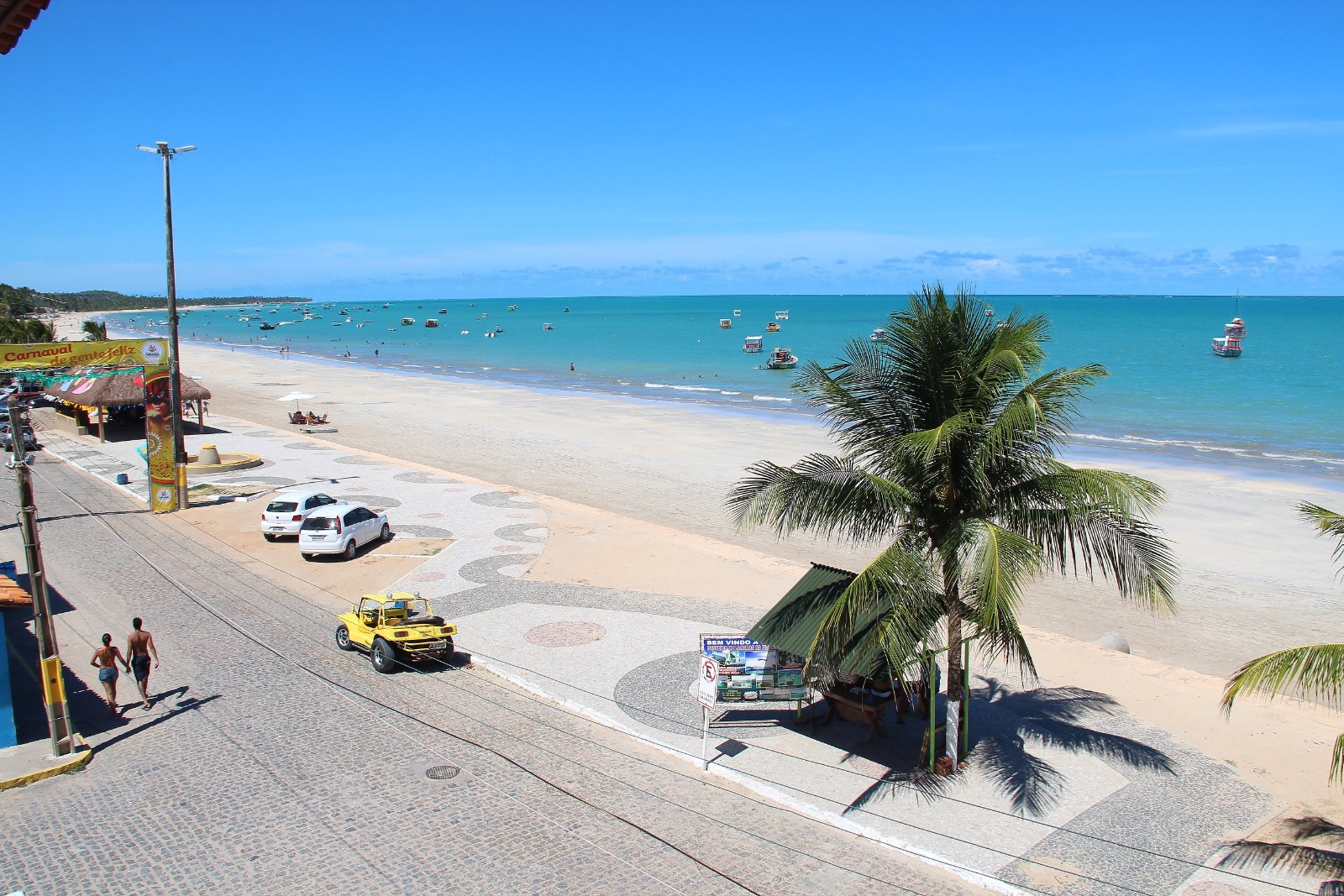 Orla de Maragogi com calçadão, coqueiro e mar verde-azulado na maré baixa