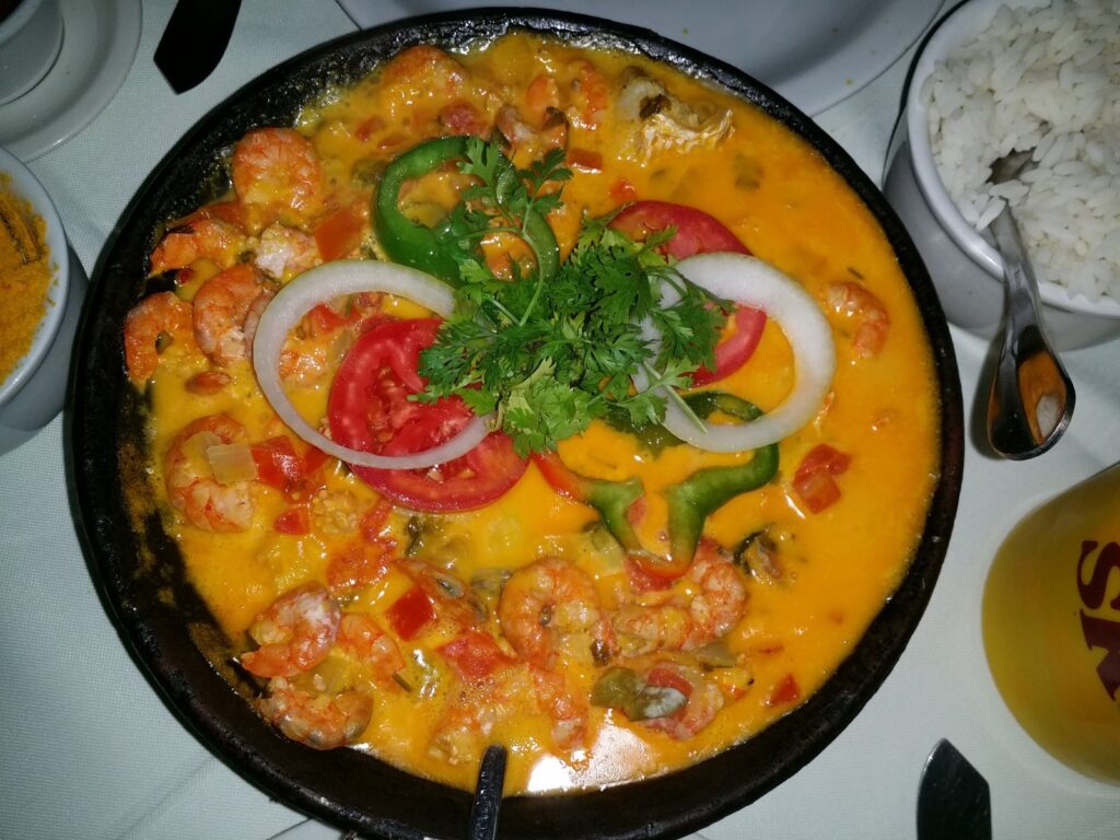 Moqueca baiana de camarão servida na panela, com tomate, cebola e coentro