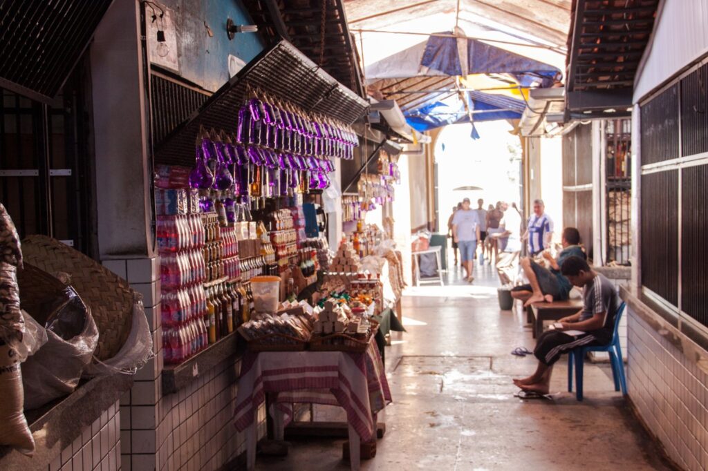 Corredor de feira no Centro Histórico de São Luís com bancas de produtos regionais, garrafas e cestos