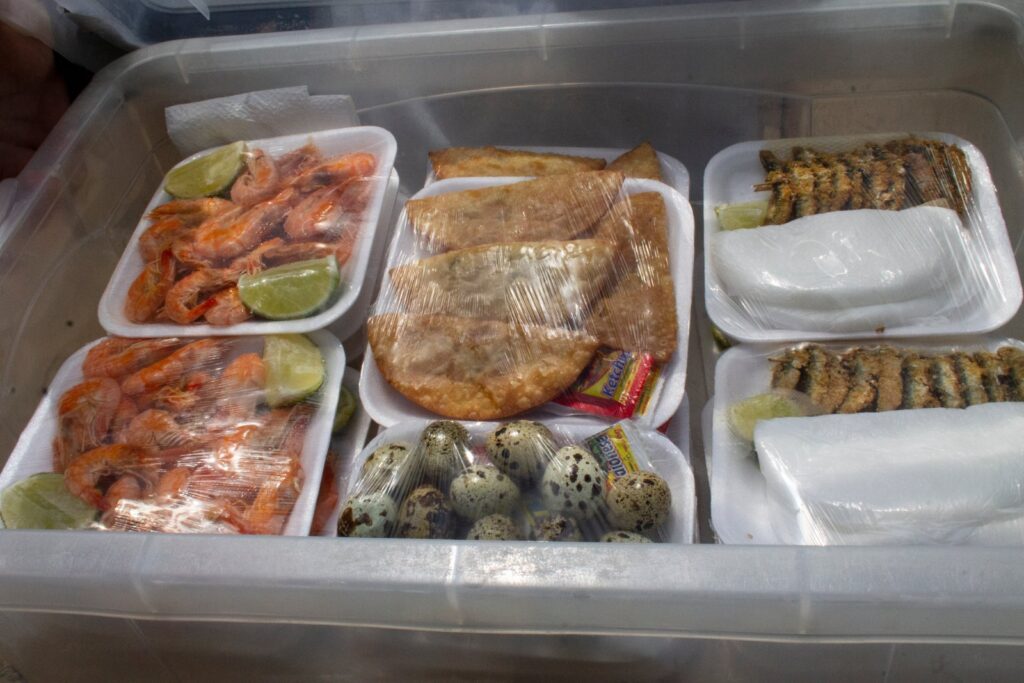 Caixa de vendedor de praia com camarão com limão, pastel, ovos de codorna e ginga com tapioca