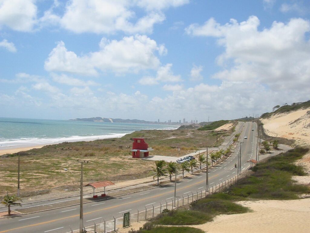 Via Costeira vista do alto do Parque das Dunas, com a estrada entre as dunas e o mar e Ponta Negra ao fundo