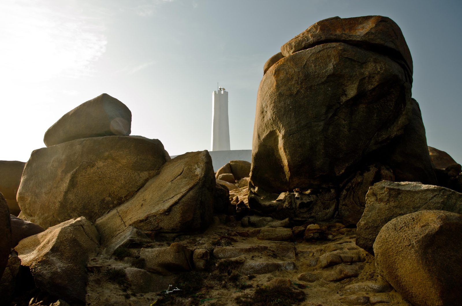 Farol da Pedra do Sal entre grandes pedras na praia, em Parnaíba