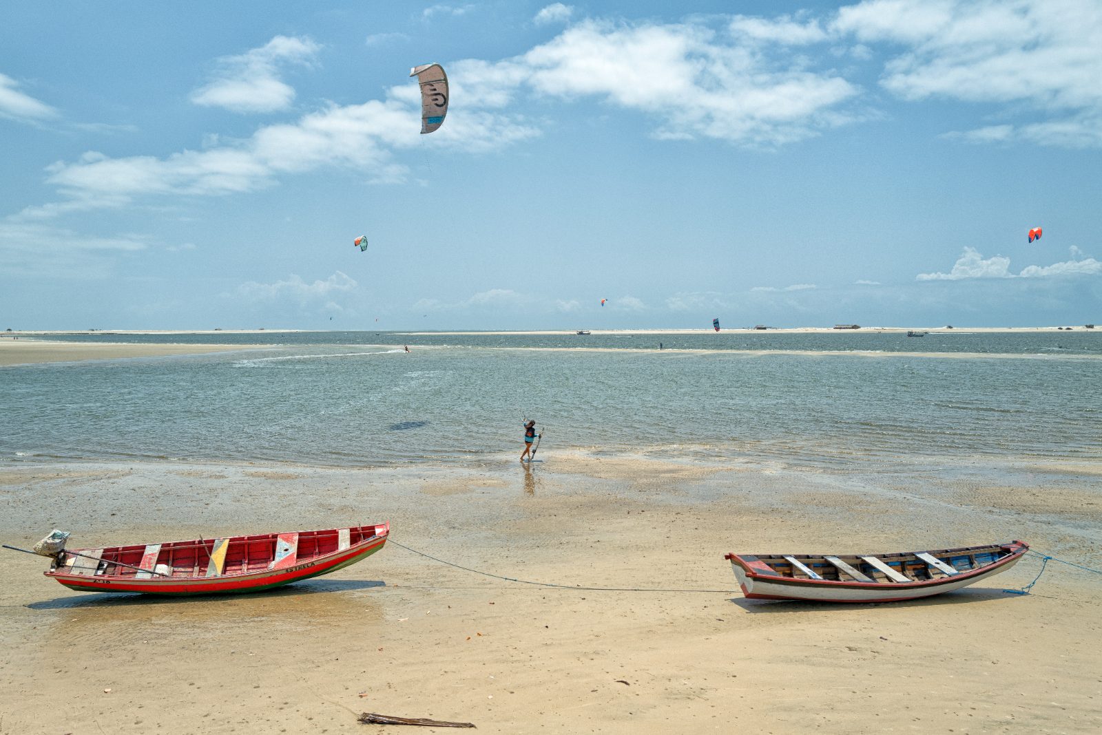 Barcos de pesca na areia e kitesurfistas ao fundo na praia de Atins