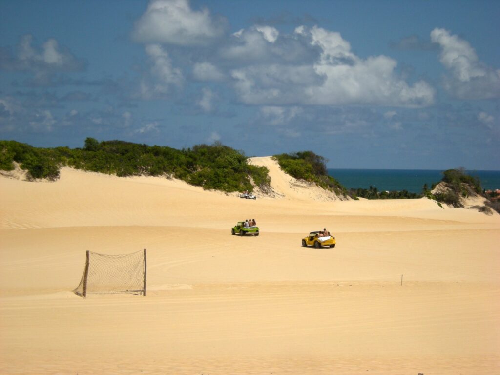 Dois buggies atravessando as dunas de Jacumã, no litoral norte de Natal, com o mar ao fundo