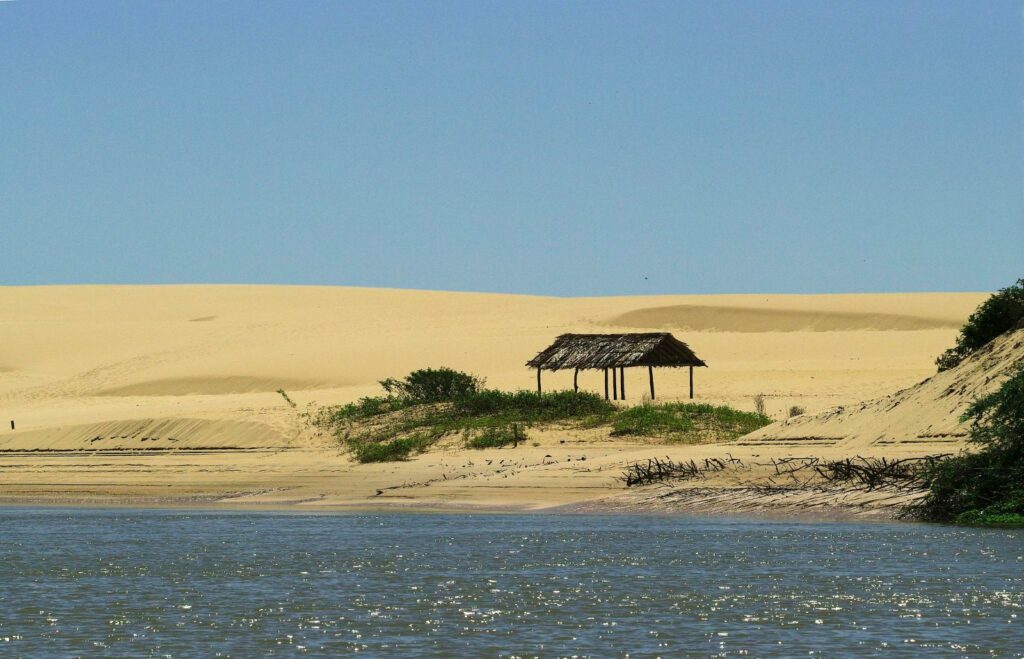 Dunas claras na margem de um braço do Delta do Parnaíba, com uma pequena cobertura de palha à beira da água