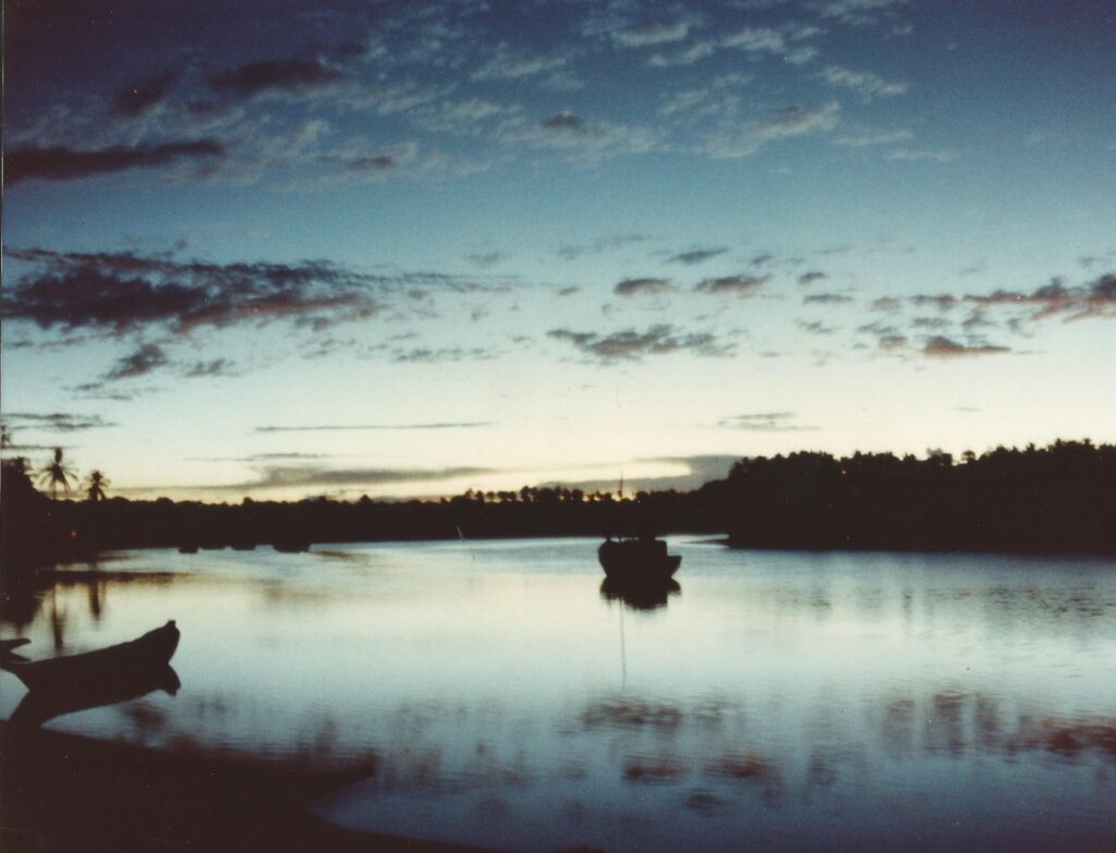 Rio Caraíva ao entardecer, com canoas paradas na água e a mata escura na outra margem