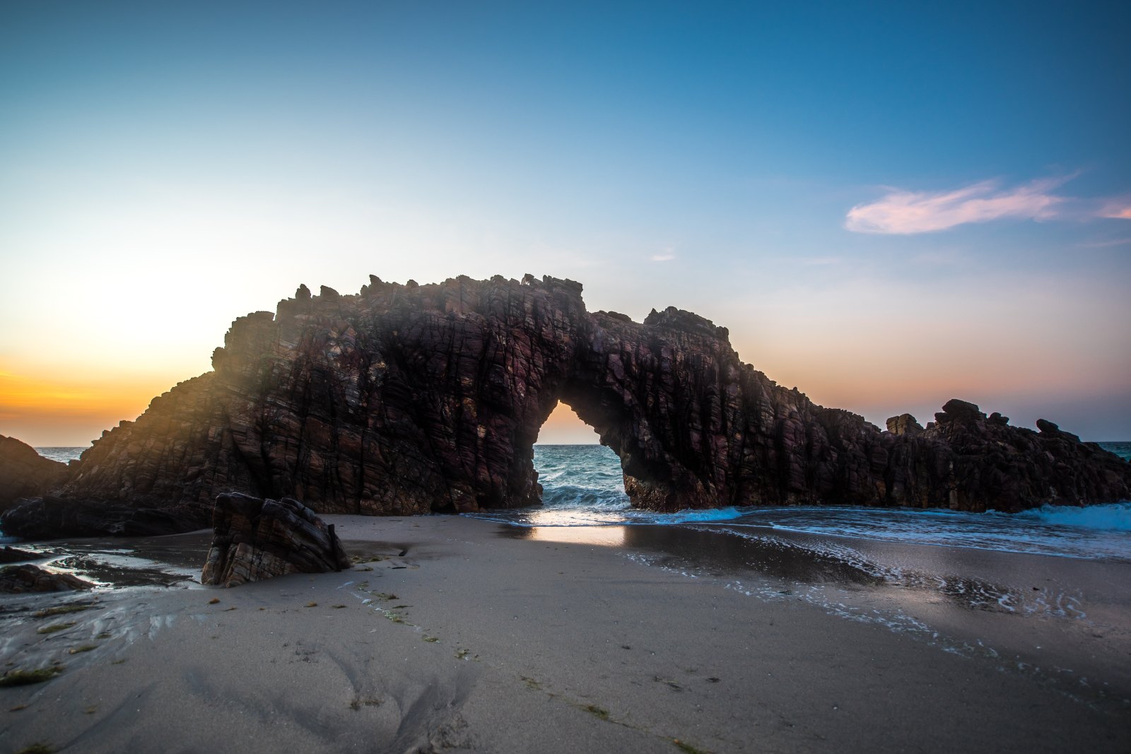 Pedra Furada, arco de rocha na beira do mar de Jericoacoara, com o sol se pondo no vão da pedra