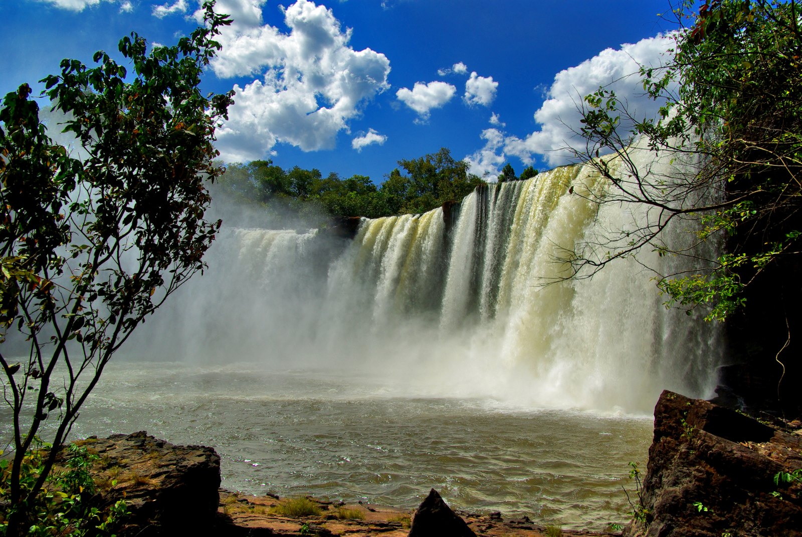 Cachoeira de São Romão, larga queda d'água no rio Farinha, cercada de mata e céu azul com nuvens, no Parque Nacional da Chapada das Mesas