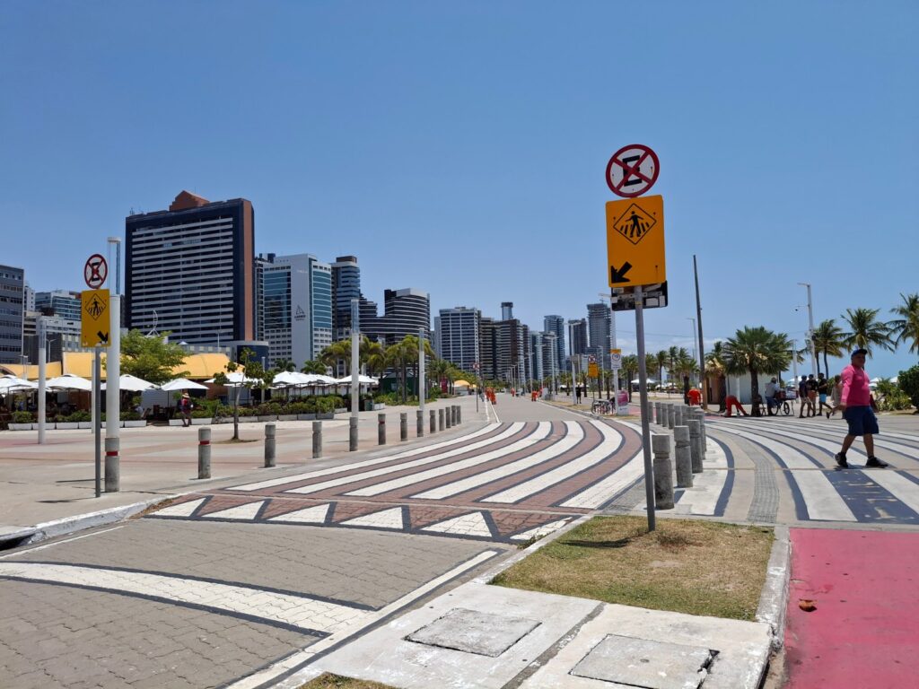 Calçadão da Avenida Beira-Mar com ciclofaixa, barracas da feirinha e prédios de hotéis ao fundo, em Fortaleza