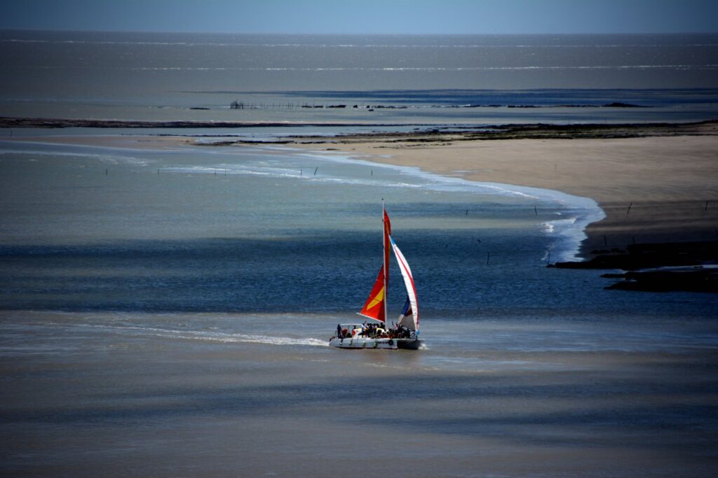 Barco com vela vermelha e branca navegando perto da costa de Alcântara, no Maranhão