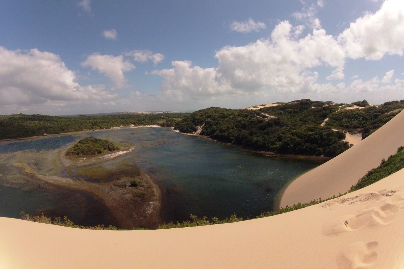 Vista do alto de uma duna para a Lagoa de Pitangui, cercada de vegetação, no litoral norte de Natal