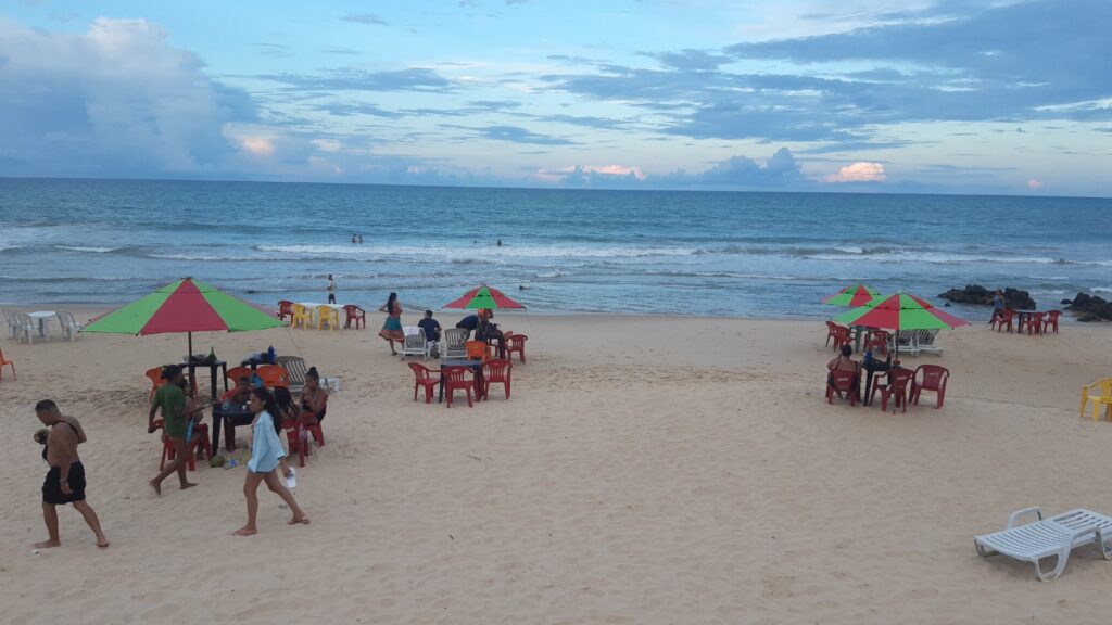 Barracas com guarda-sóis coloridos na areia da Praia do Meio, em Natal, com o mar ao fundo
