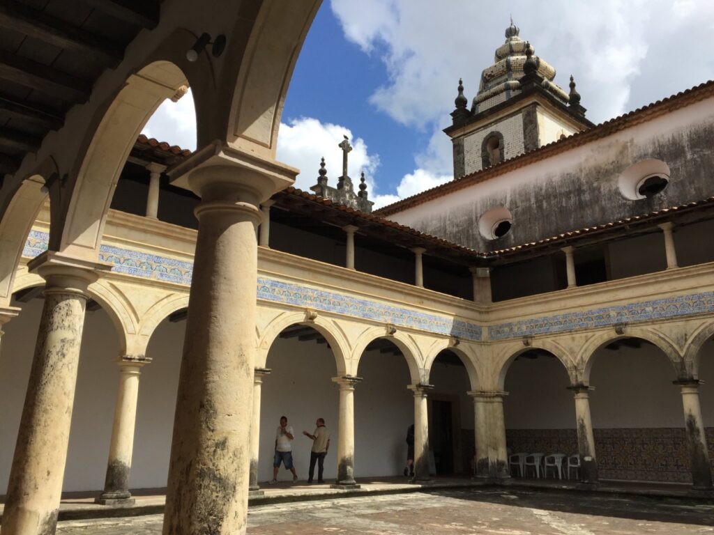 Claustro do Centro Cultural São Francisco, em João Pessoa, com arcos, colunas e azulejos e a torre barroca da igreja ao fundo