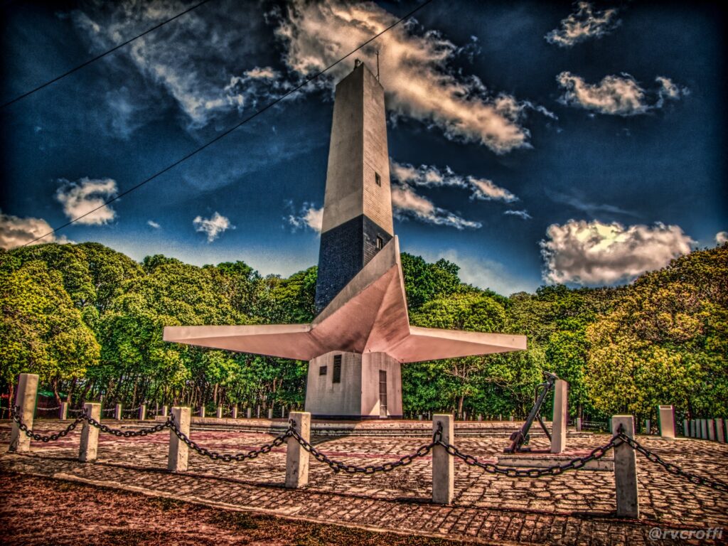 Farol do Cabo Branco, torre branca de concreto em forma de estrela de três pontas, cercada de mata no alto da falésia