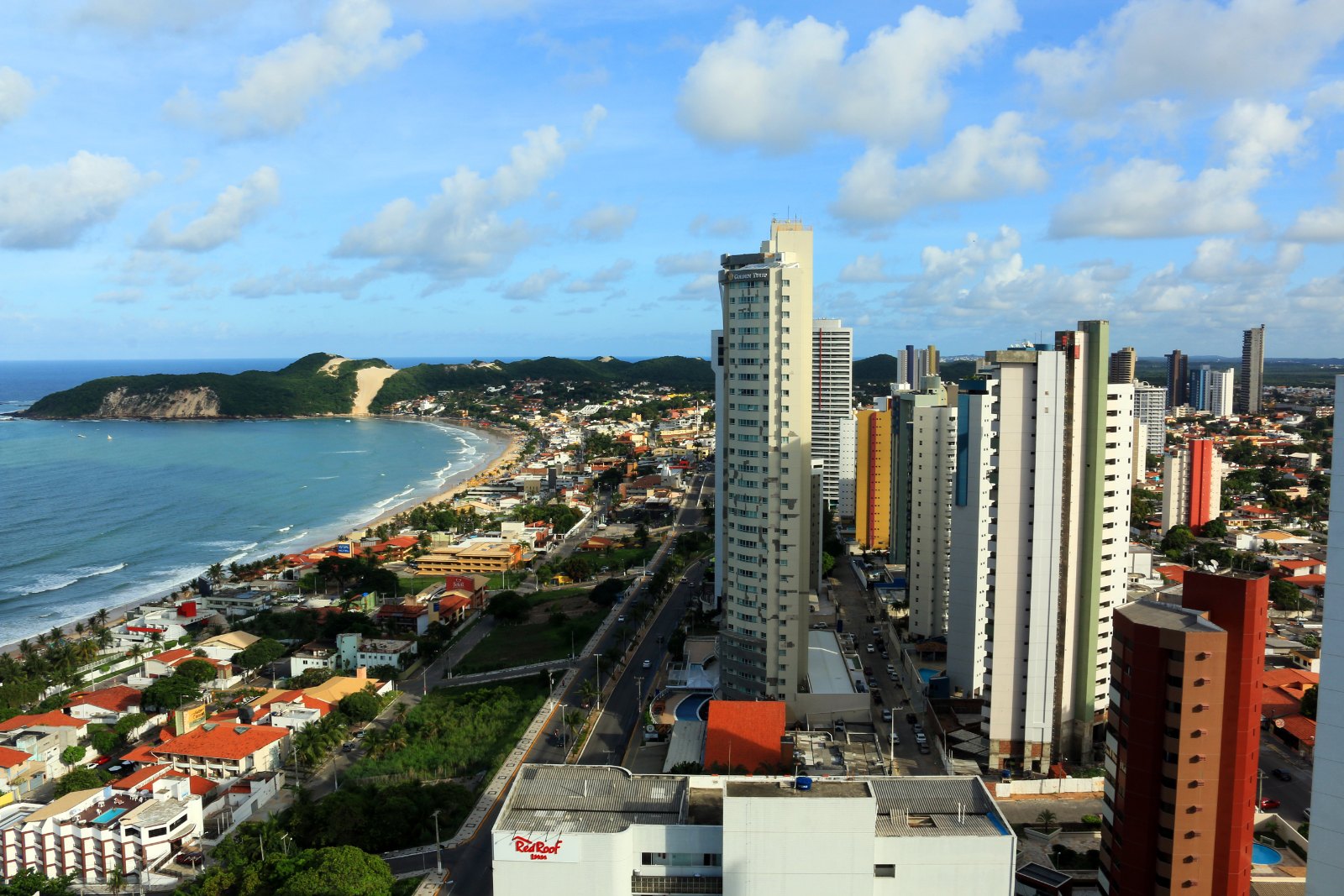 Vista aérea da praia de Ponta Negra, em Natal, com prédios à beira-mar e o Morro do Careca ao fundo