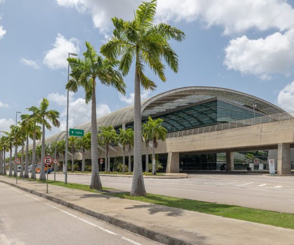 Fachada do Aeroporto Internacional de Natal, em São Gonçalo do Amarante, com palmeiras imperiais na via de acesso