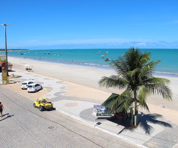 Orla de Maragogi com calçadão, coqueiro e mar verde-azulado na maré baixa