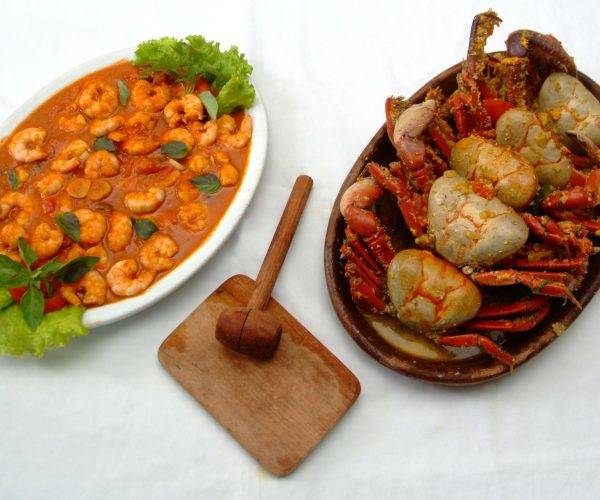 Prato de camarão ao molho e travessa de caranguejos com martelinho de madeira, pratos típicos de Natal
