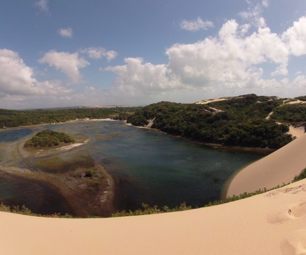 Vista do alto de uma duna para a Lagoa de Pitangui, cercada de vegetação, no litoral norte de Natal