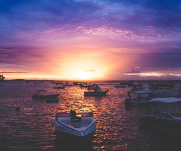 Barcos ancorados no mar de Morro de São Paulo ao pôr do sol, com céu lilás e laranja